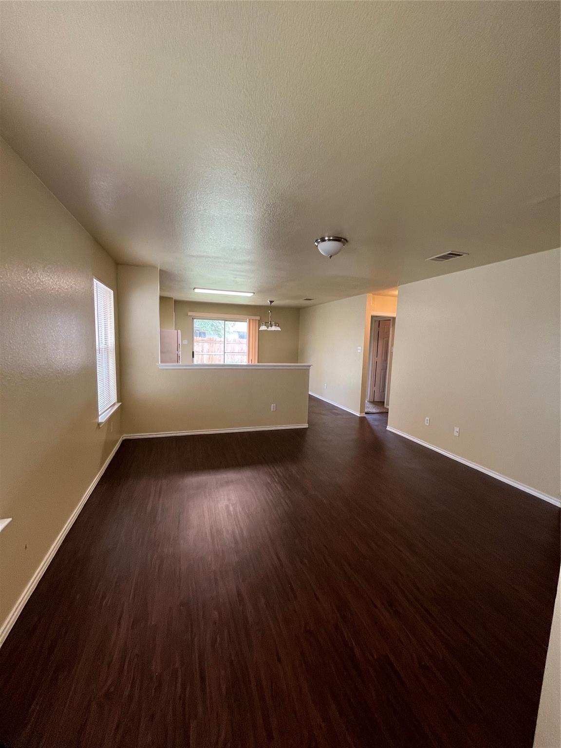 3001 Caleb Drive Austin, TX 78725 - Photo 3 of 16 Empty room featuring dark wood-style flooring, a textured ceiling, and a chandelier