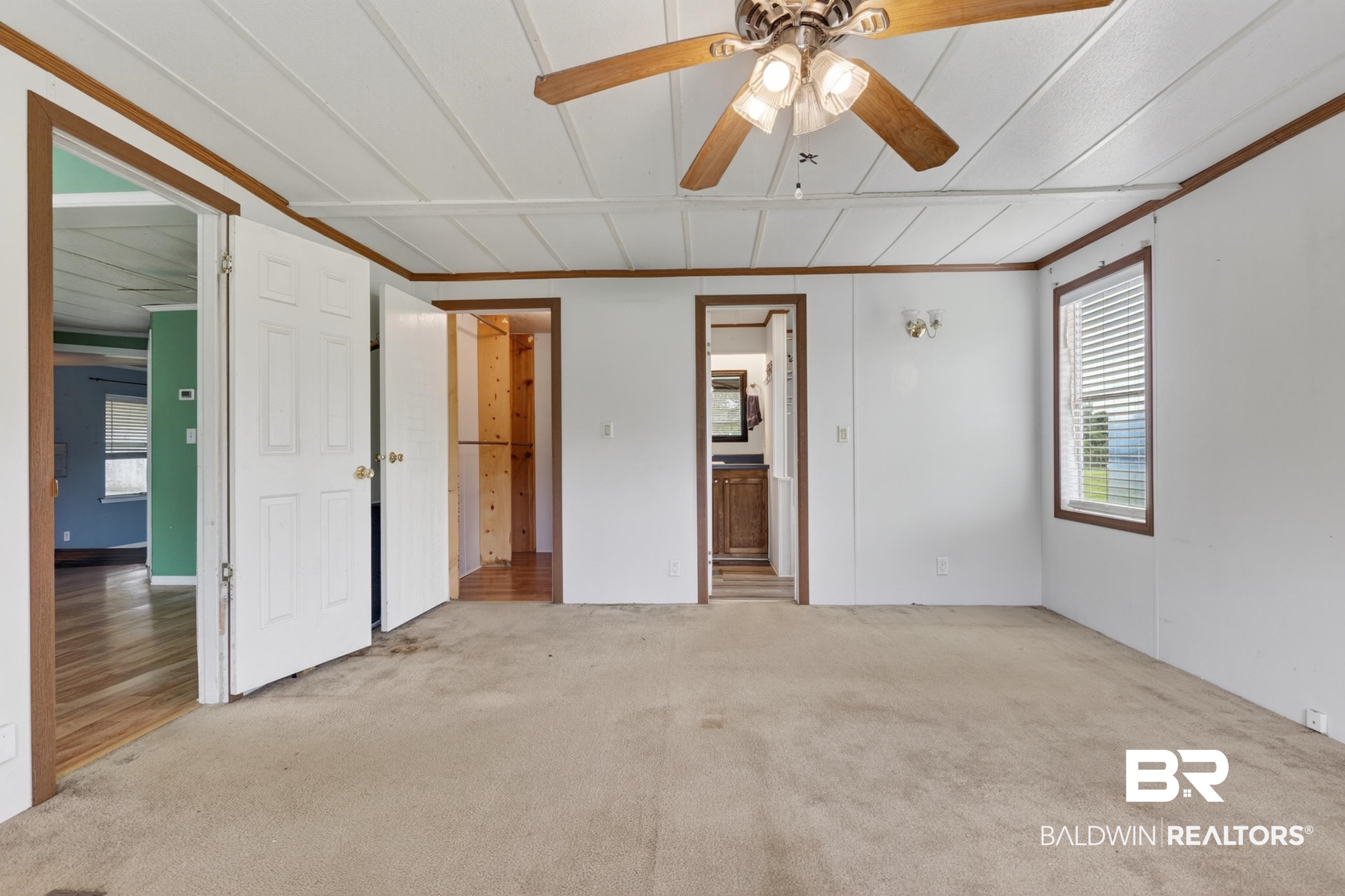 24903 Patterson Road Robertsdale, AL 36567 - Photo 41 of 57 Spacious room featuring neutral carpeting, white paneled walls with wood trim, and a ceiling fan with integrated lighting