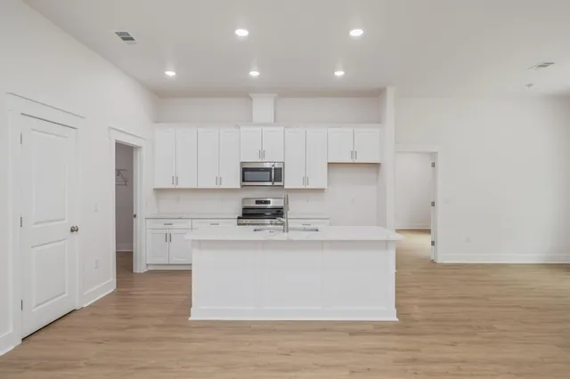 a kitchen with kitchen island a sink a stove a refrigerator and white cabinets