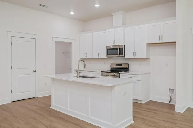 a kitchen with stainless steel appliances granite countertop a sink stove and microwave with wooden floor