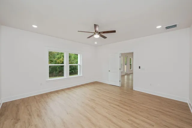 an empty room with wooden floor and windows