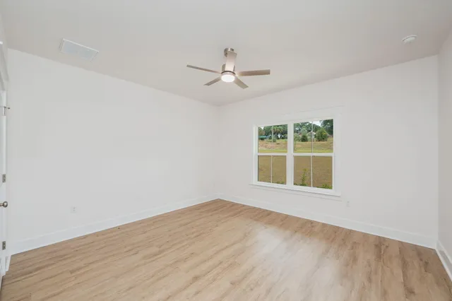 an empty room with a window and ceiling fan