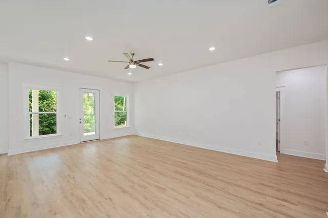 a view of an empty room with a window and wooden floor