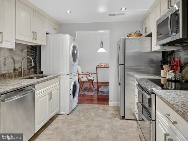 a kitchen with stainless steel appliances granite countertop a refrigerator a stove and a sink