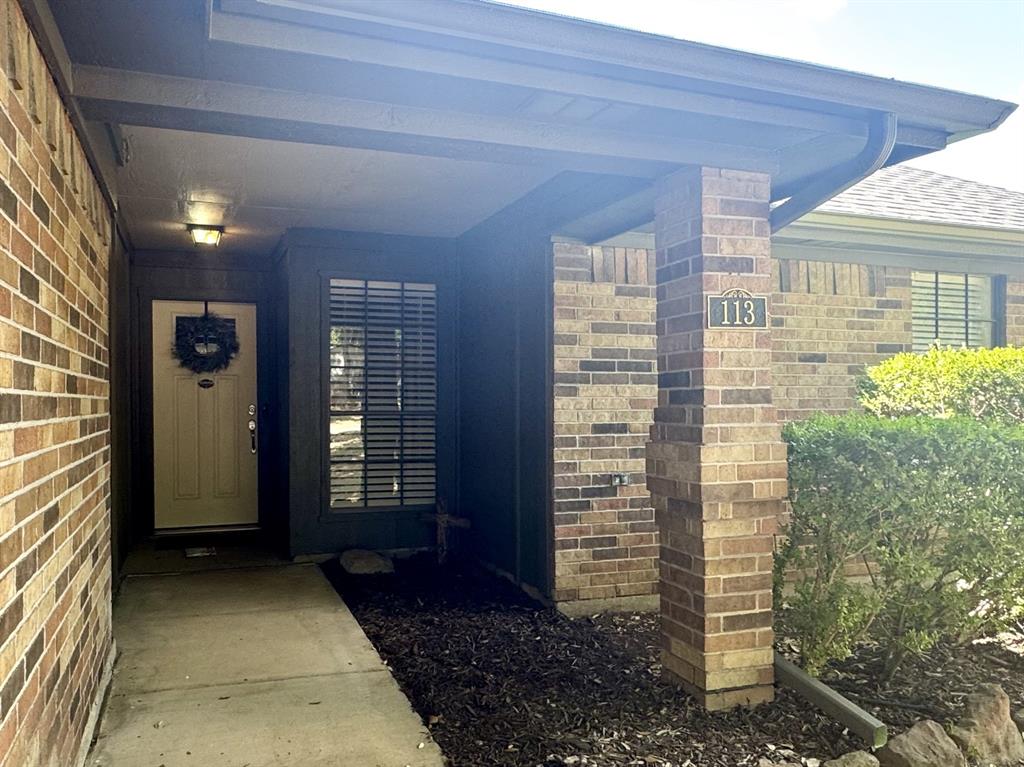 113 Northeast Timber Ridge Drive Burleson, TX 76028 - Photo 3 of 36 Inviting Covered Front Porch featuring brick column with address marker, rain gutters, an exterior light fixture, and a vertical window with horizontal blinds.
