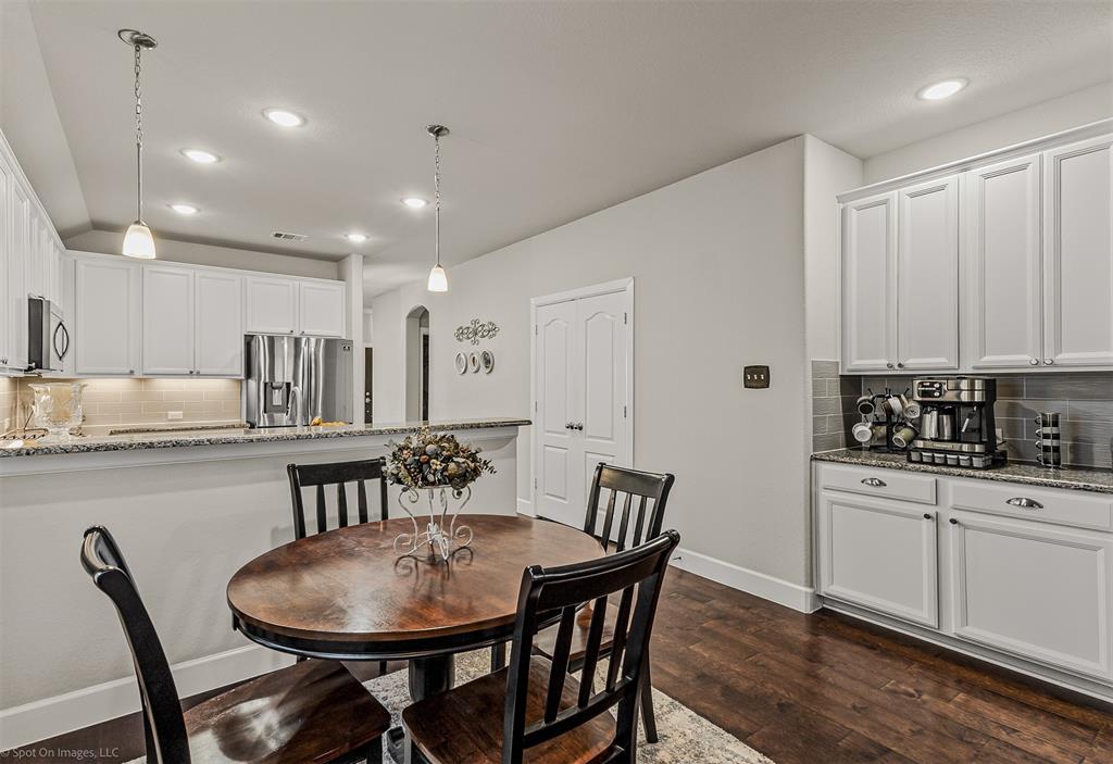2064 Glaston Road Forney, TX 75126 - Photo 10 of 36 a kitchen with stainless steel appliances kitchen island granite countertop a dining table chairs and white cabinets