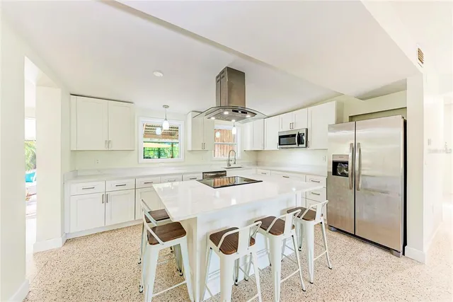 a kitchen with stainless steel appliances kitchen island granite countertop a refrigerator and a stove top oven