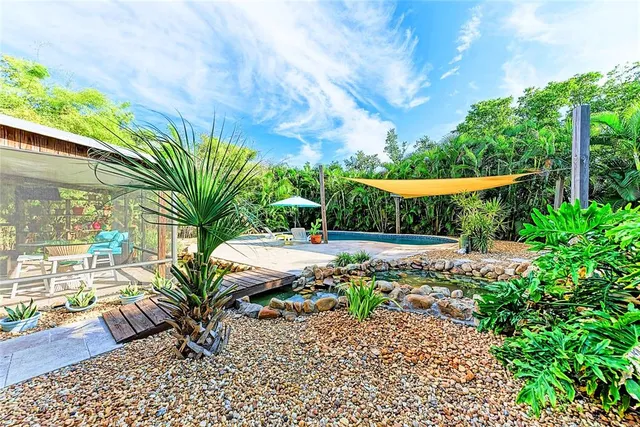 a view of a yard with plants and a lawn chair under an umbrella