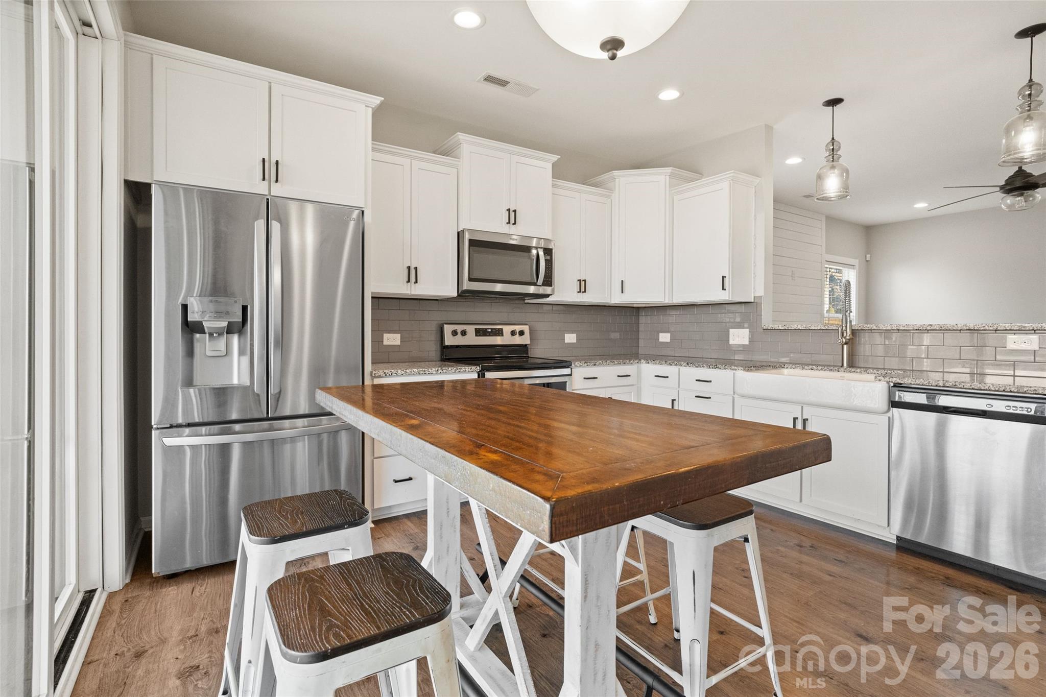 21260 Sanctuary Drive Lancaster, SC 29720 - Photo 12 of 44 a kitchen with stainless steel appliances granite countertop a stove a refrigerator a sink a microwave and white cabinets with wooden floor