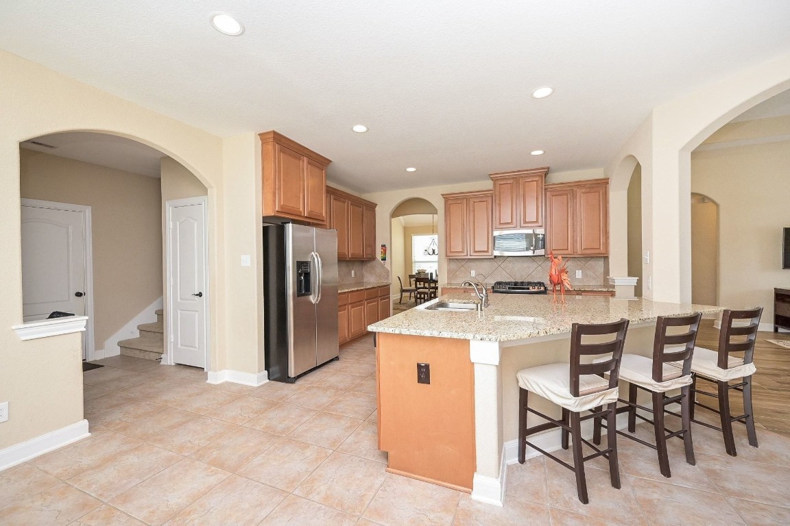 107 North Bacopa Drive Spring, TX 77389 - Photo 17 of 34 Open kitchen layout with a generous island and bar seating, seamlessly flowing into the main living space and nearby dining areas.
