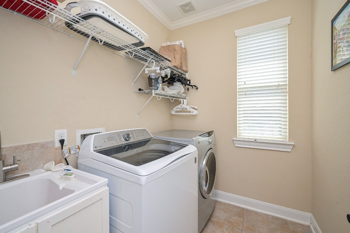 107 North Bacopa Drive Spring, TX 77389 - Photo 28 of 34 Laundry room with built-in shelving and a window for natural light, offering a functional and organized space.