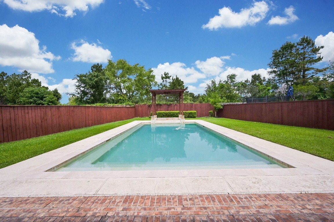 107 North Bacopa Drive Spring, TX 77389 - Photo 31 of 34 Peaceful pool view framed by mature trees and privacy fencing, creating a calm and inviting outdoor setting.