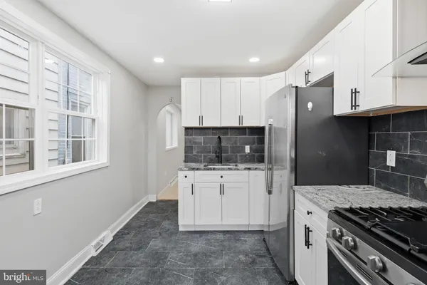 a kitchen with granite countertop a stove sink and refrigerator