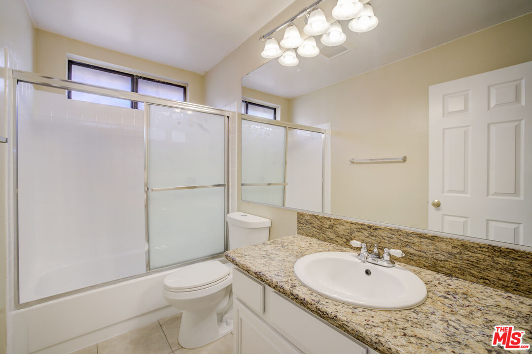 214 South Raspberry Lane Anaheim, CA 92808 - Photo 33 of 35 a bathroom with a granite countertop sink toilet a mirror and shower