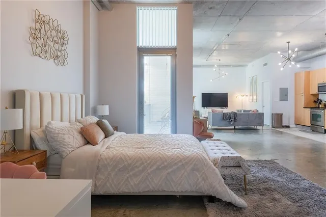 a bedroom with a large bed a couch and chandelier