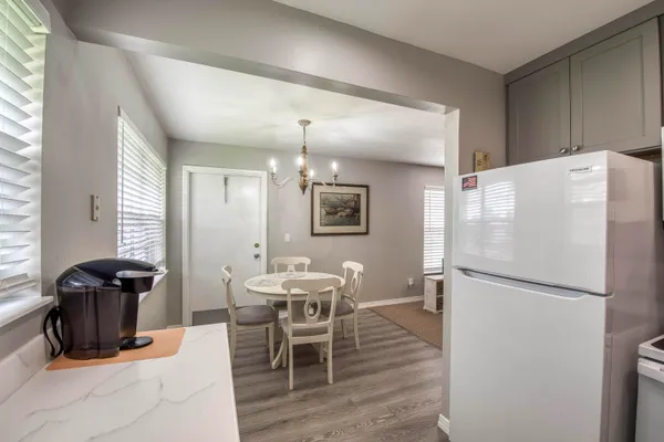 a kitchen with stainless steel appliances a refrigerator a stove a dining table and chairs with wooden floor