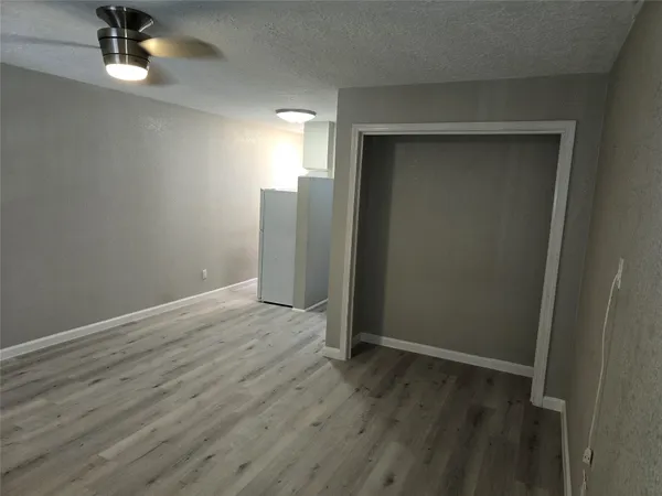 an empty room with wooden floor cabinet and windows