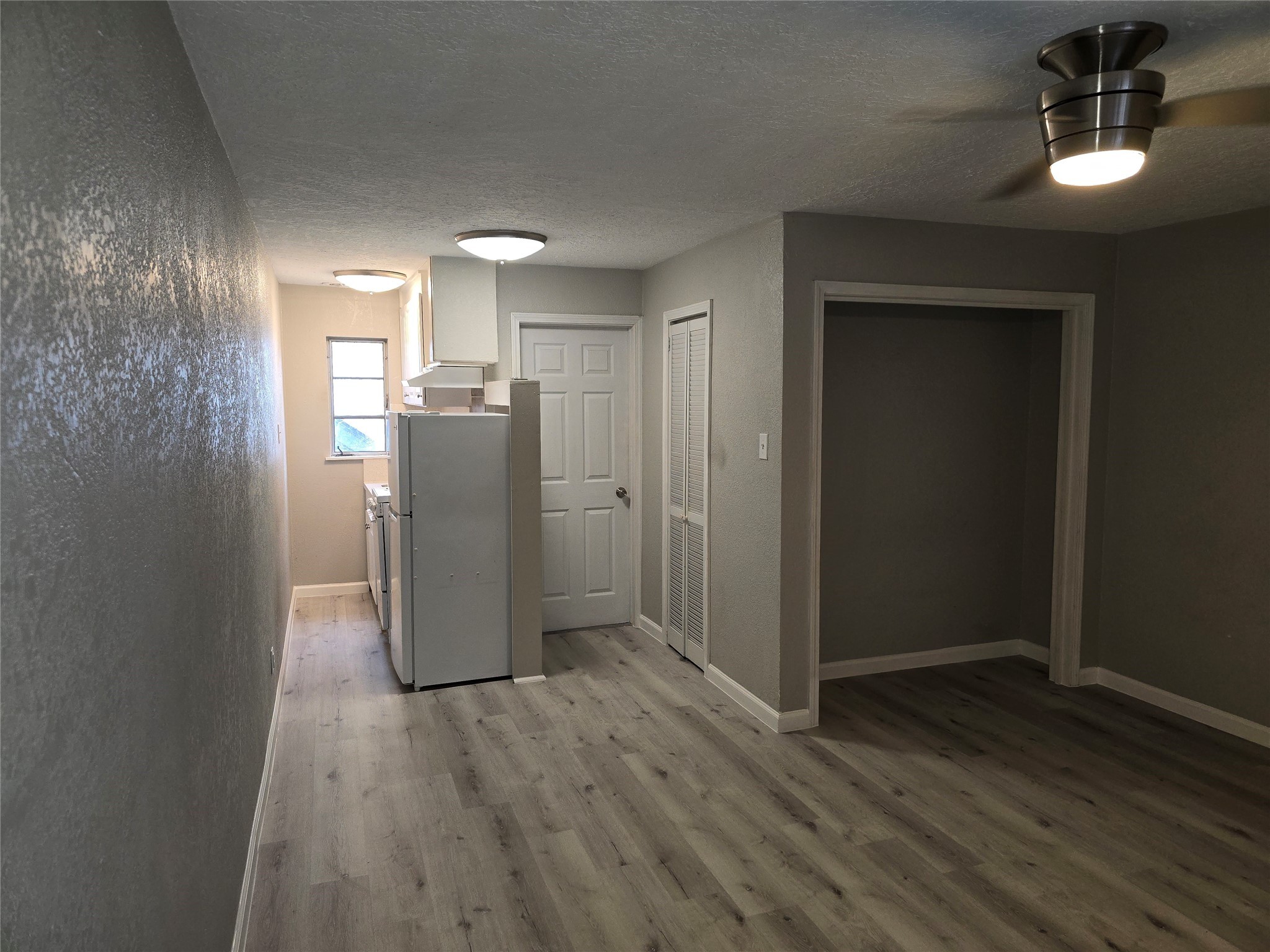 2501 Yoakum Boulevard, Unit 13 Houston, TX 77006 - Photo 6 of 24 a view of a refrigerator in kitchen and an empty room with wooden floor windows