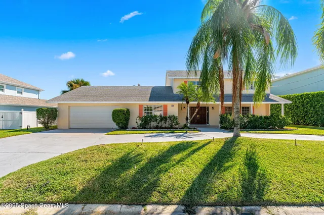 a view of a house with a yard and palm trees