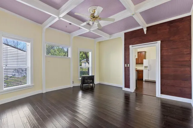 a view of an empty room with window and wooden floor