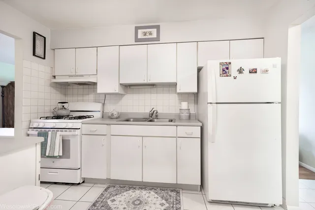 a kitchen with a sink a refrigerator and white cabinets
