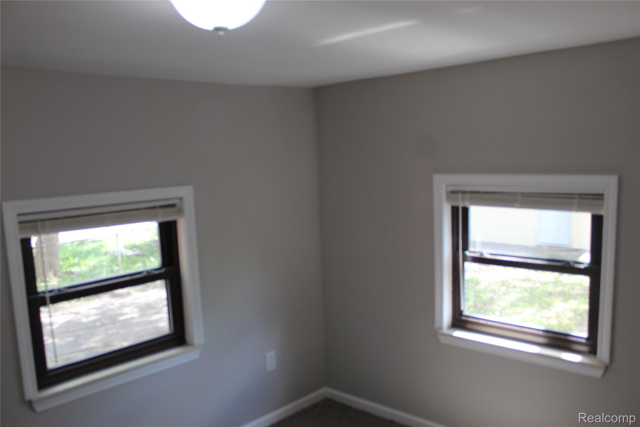 5543 Balfour Road Detroit, MI 48224 - Photo 18 of 54 Room featuring two double-hung windows with white trim, a flush-mount ceiling light fixture, neutral gray wall paint, and gray carpeting
