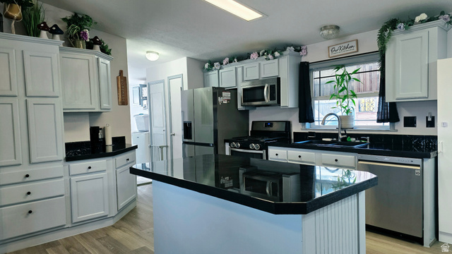 401 West 2000th Street South Vernal, UT 84078 - Photo 4 of 26 Kitchen featuring a central island with a dark countertop, light-toned cabinetry, stainless steel appliances, a double basin sink, and wood-finish flooring