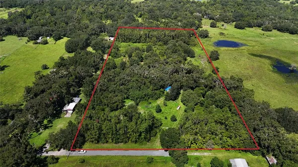 an aerial view of a house with a yard and covered with trees