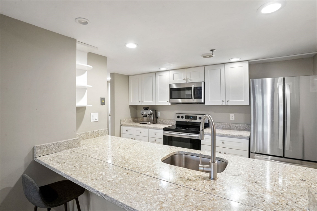 20 Webster Street, Unit 605 Brookline, MA 02446 - Photo 11 of 40 a kitchen with granite countertop a stove refrigerator and microwave