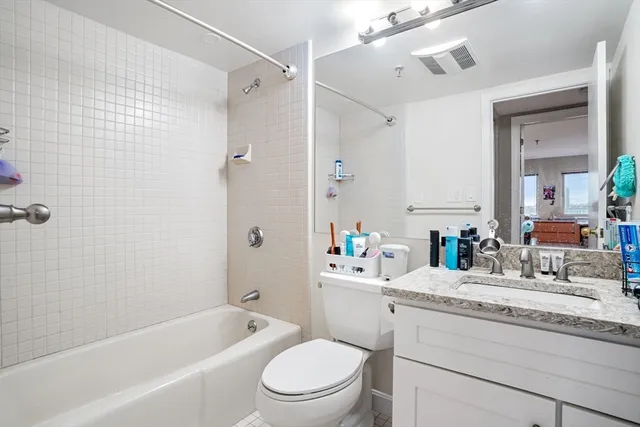 a bathroom with a granite countertop bathtub shower sink vanity mirror and toilet