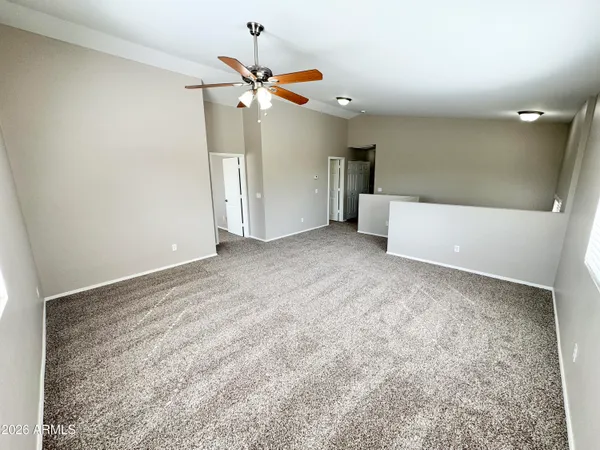 an empty room with a ceiling fan and carpet