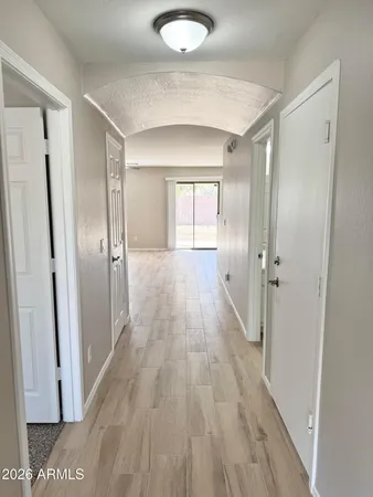 a view of a hallway with wooden floor and a bathroom