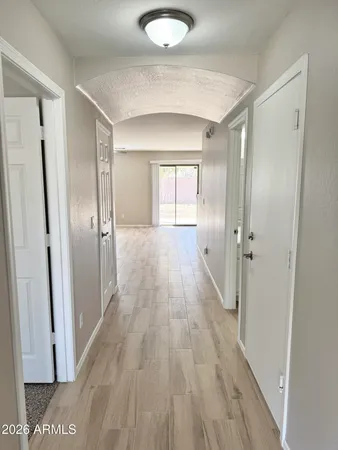 a view of a hallway with wooden floor and a bathroom