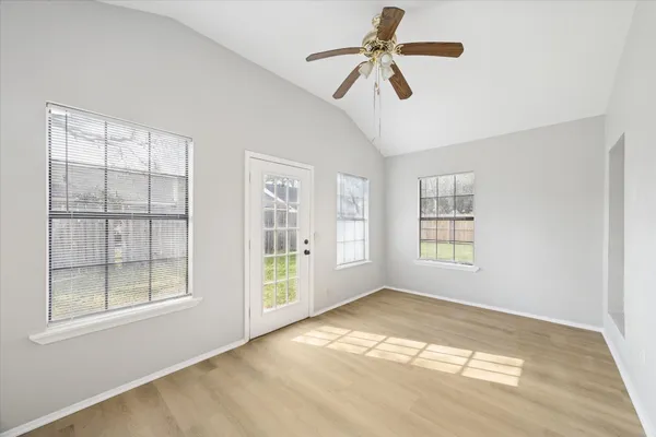 a view of empty room with wooden floor and fan