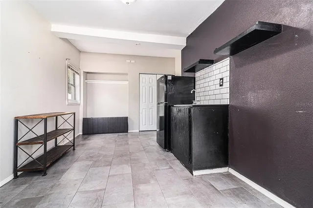 a view of a refrigerator in kitchen and an empty room