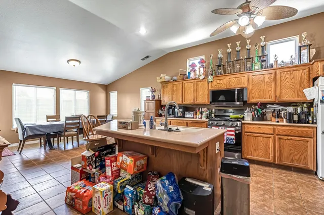 a kitchen with stainless steel appliances granite countertop a stove top oven a dining table and chairs with the living room
