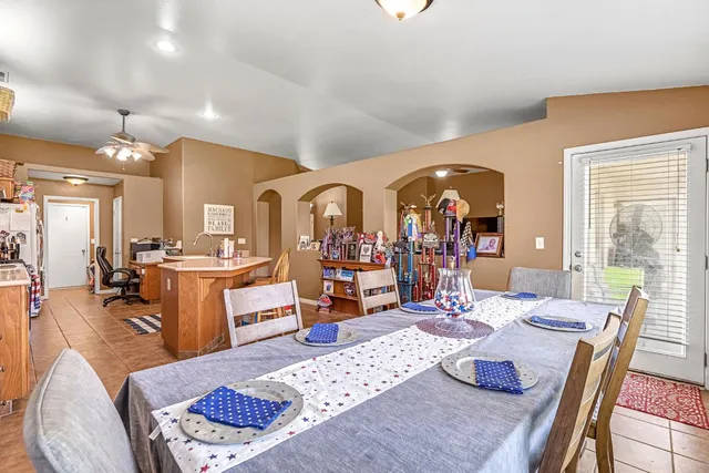 a living room with furniture a rug kitchen view and a large window