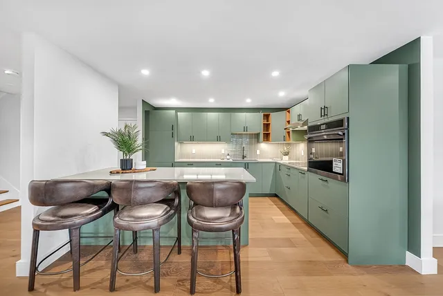 a kitchen with stainless steel appliances kitchen island granite countertop a kitchen island and chairs in it