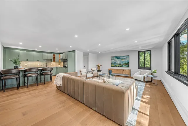 a living room with furniture kitchen view and a large window