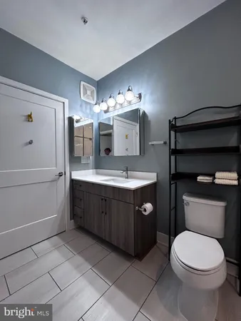 a bathroom with a toilet sink vanity granite and mirror