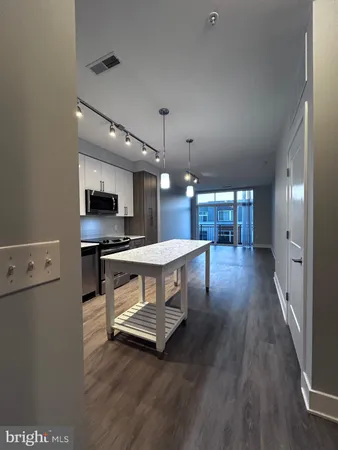 a living room with stainless steel appliances kitchen island a table and chairs in it