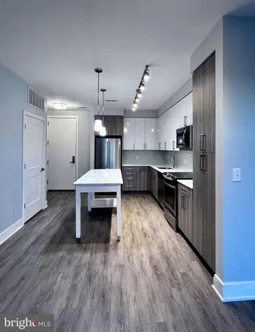 a living room with stainless steel appliances kitchen island hardwood floor and a sink