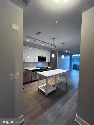 a living room with kitchen view and a wooden floor