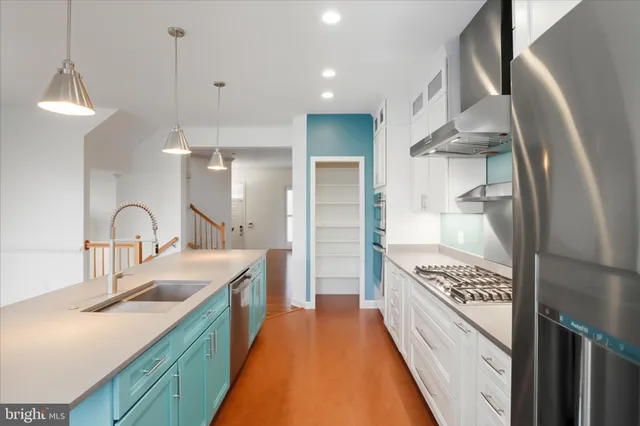 a large kitchen with kitchen island a large counter top a sink a stove and a refrigerator