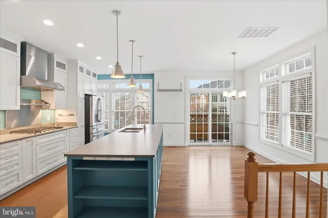 a large kitchen with kitchen island a large window a sink and a chandelier