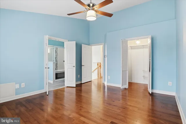 an empty room with wooden floor and a ceiling fan
