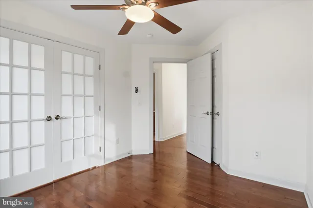 an empty room with wooden floor closet chandelier fan and windows