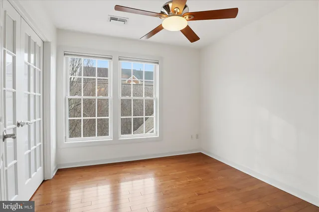 an empty room with windows and ceiling fan