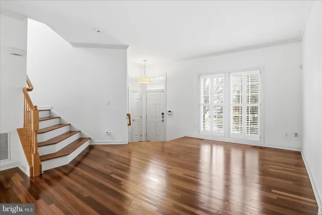a view of an empty room with wooden floor and stairs