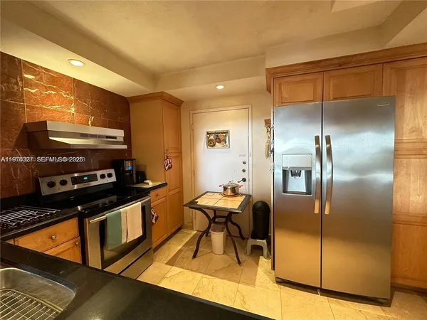 a kitchen with stainless steel appliances granite countertop a refrigerator and a stove